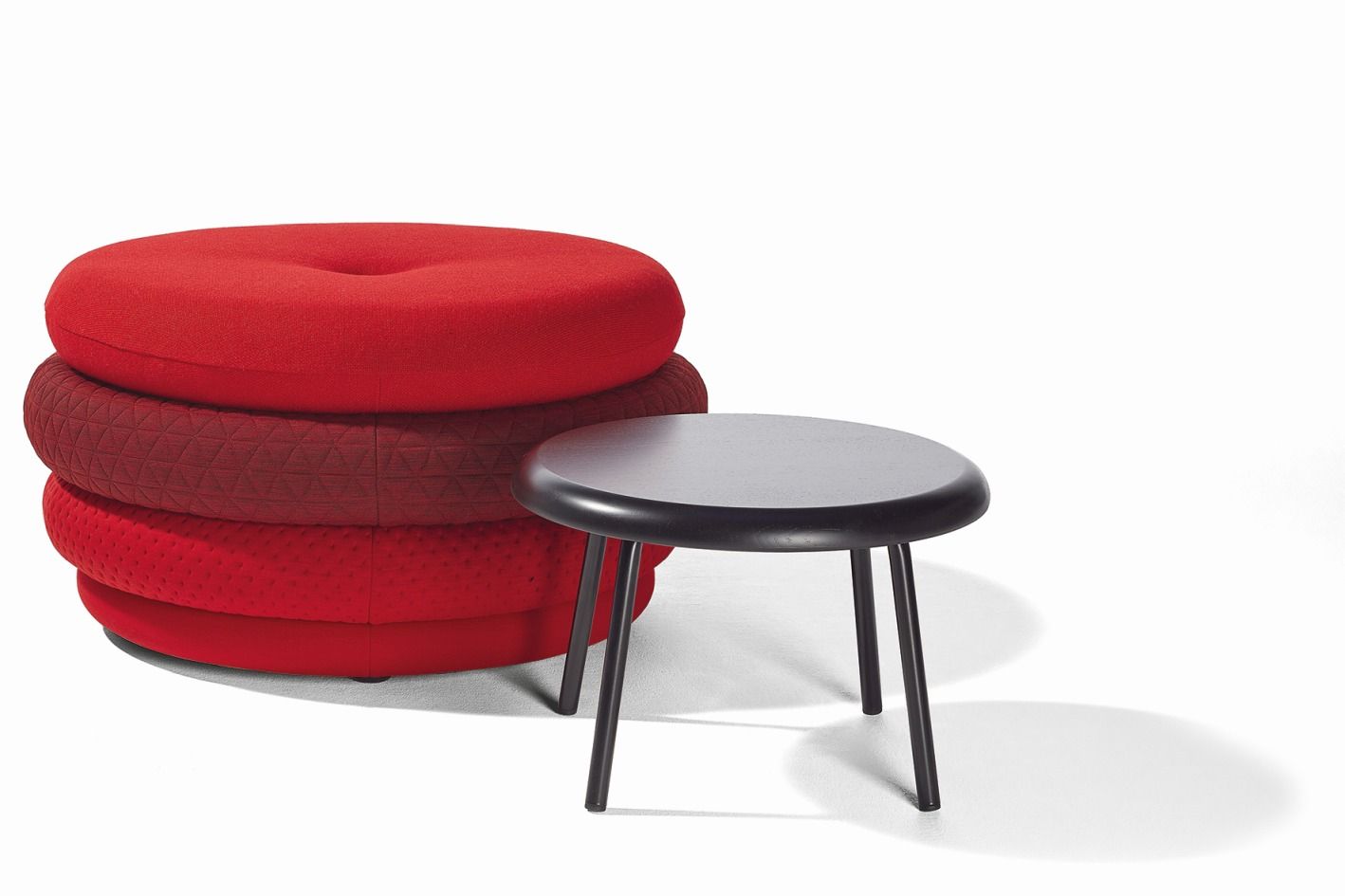 Roter Fat Tom Pouf Hocker von Richard Lampert neben einem kleinen schwarzen Tisch.