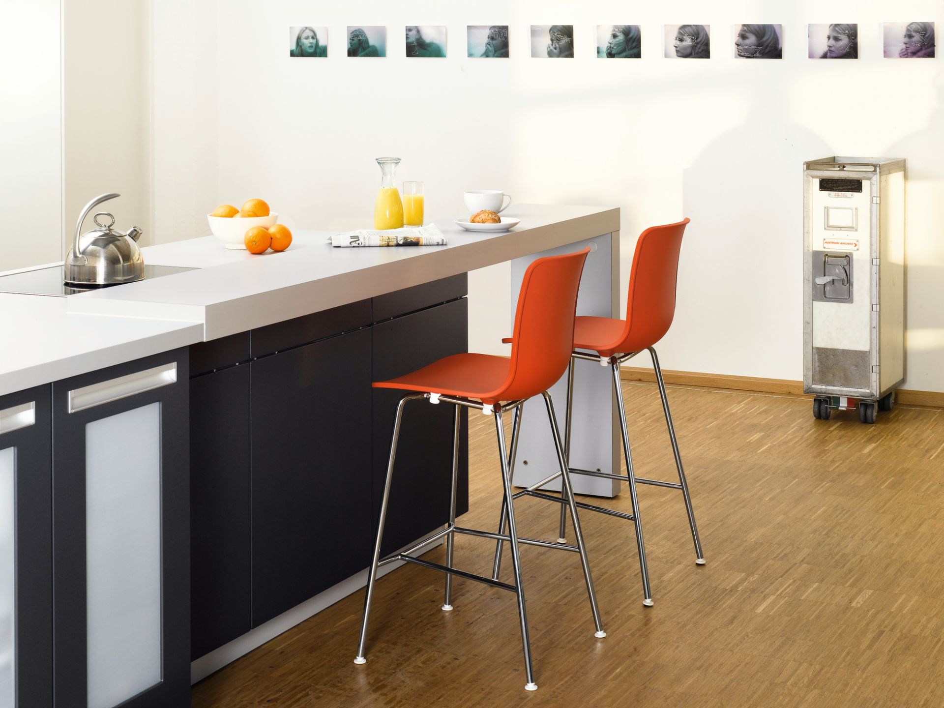 Zwei orangefarbene Hal RE Stool Barhocker von Vitra an einer Küchentheke mit Frühstücksutensilien.