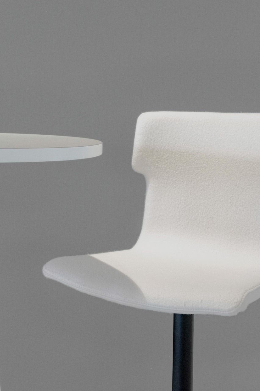Detailaufnahme des weißen Cascando Co-Chair Bürodrehstuhls mit schwarzem Fußkreuz neben einem weißen Tisch.