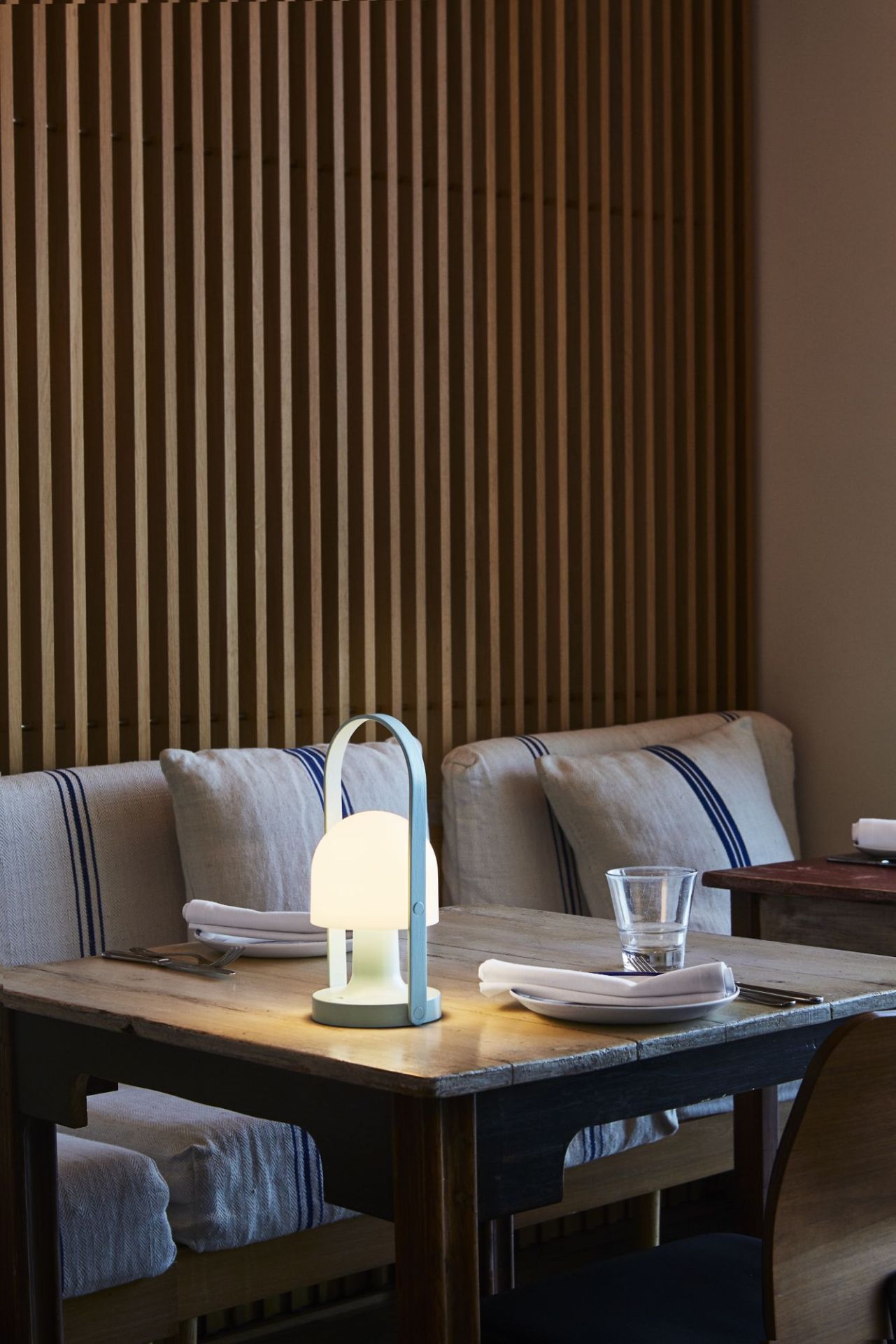 FollowMe LED Tischleuchte in Terrakotta auf gedecktem Holztisch mit Besteck und Glas.