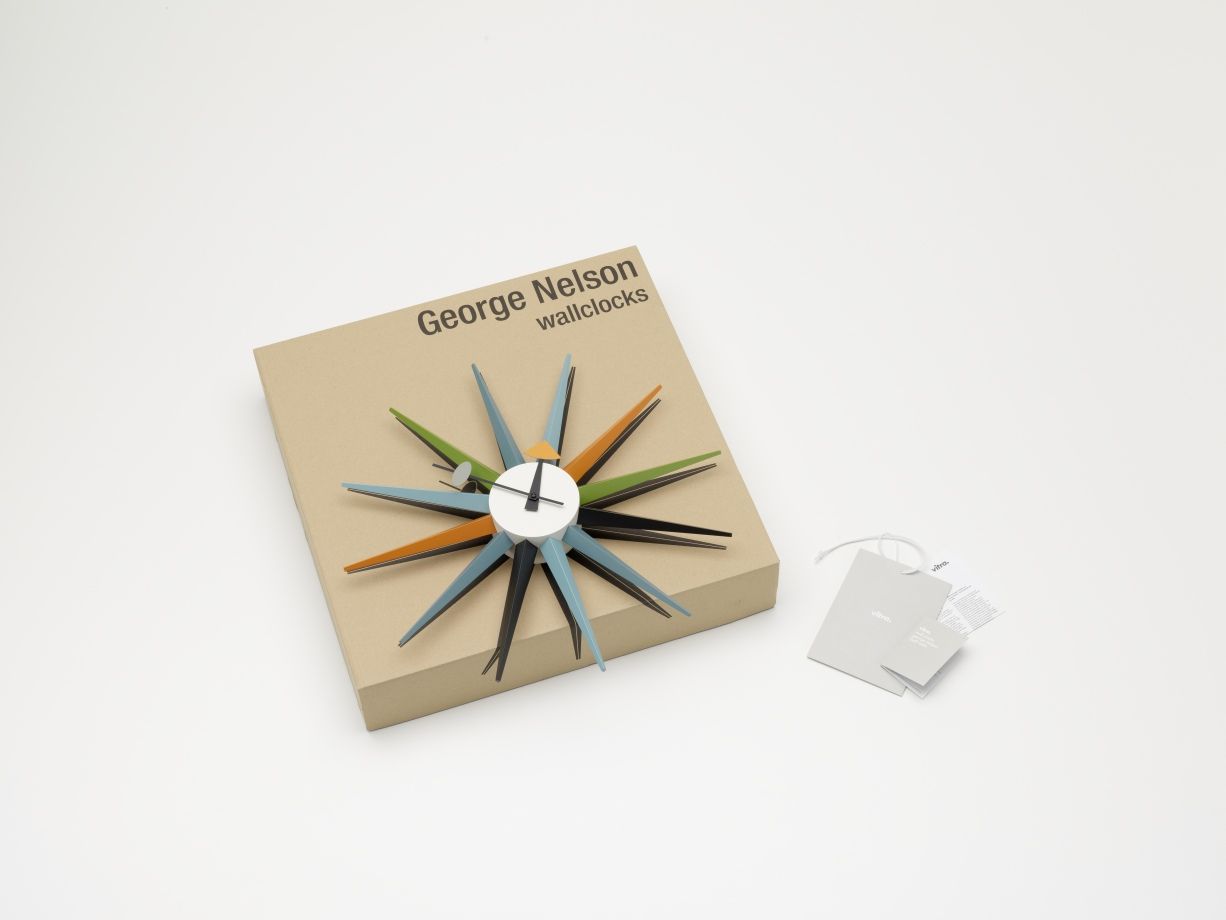 Mehrfarbige Sunburst Clock Wanduhr von Vitra auf Karton mit Etikett, modernes Designobjekt für Wohnzimmer.