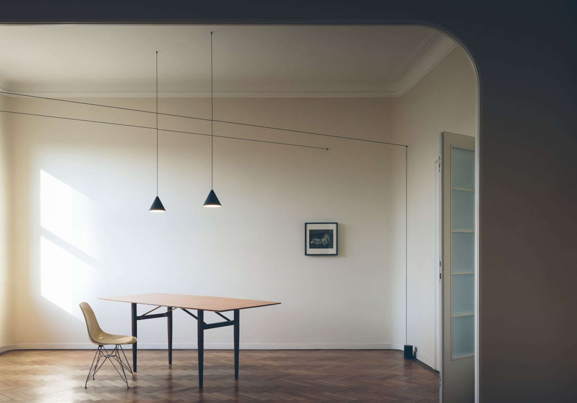 Esszimmer mit Flos String Light Kegelkopf Pendelleuchten über Holztisch und Stuhl.