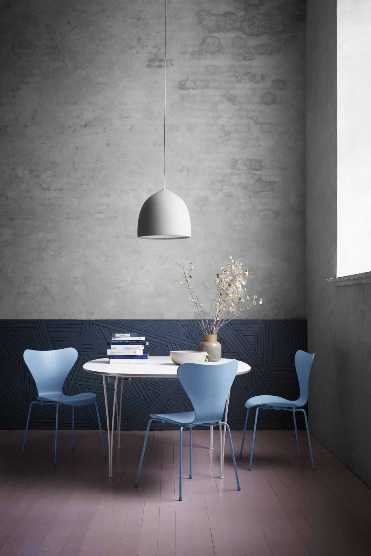Drei blaue Siebener Stühle von Fritz Hansen um einen weißen Esstisch mit Lampe.