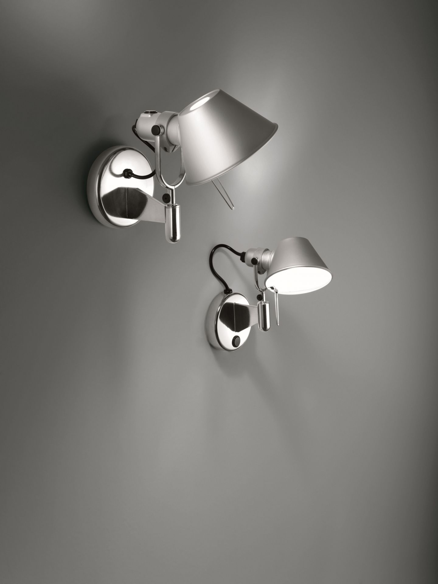 Zwei moderne Tolomeo Faretto Wandleuchten aus Aluminium von Artemide an einer grauen Wand.
