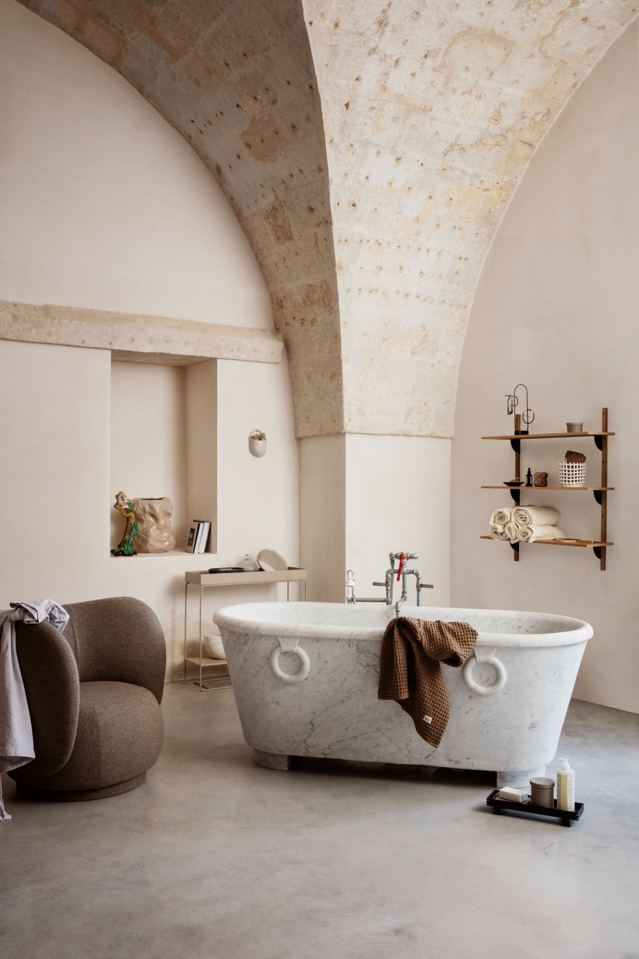 Innenaufnahme eines Badezimmers mit Rico Lounge Chair Sessel von Ferm Living und Marmorbadewanne.
