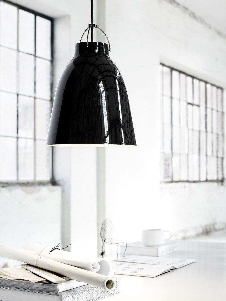 Schwarze Caravaggio Pendelleuchte von Fritz Hansen über einem Schreibtisch in einem hellen Raum mit Fenstern.