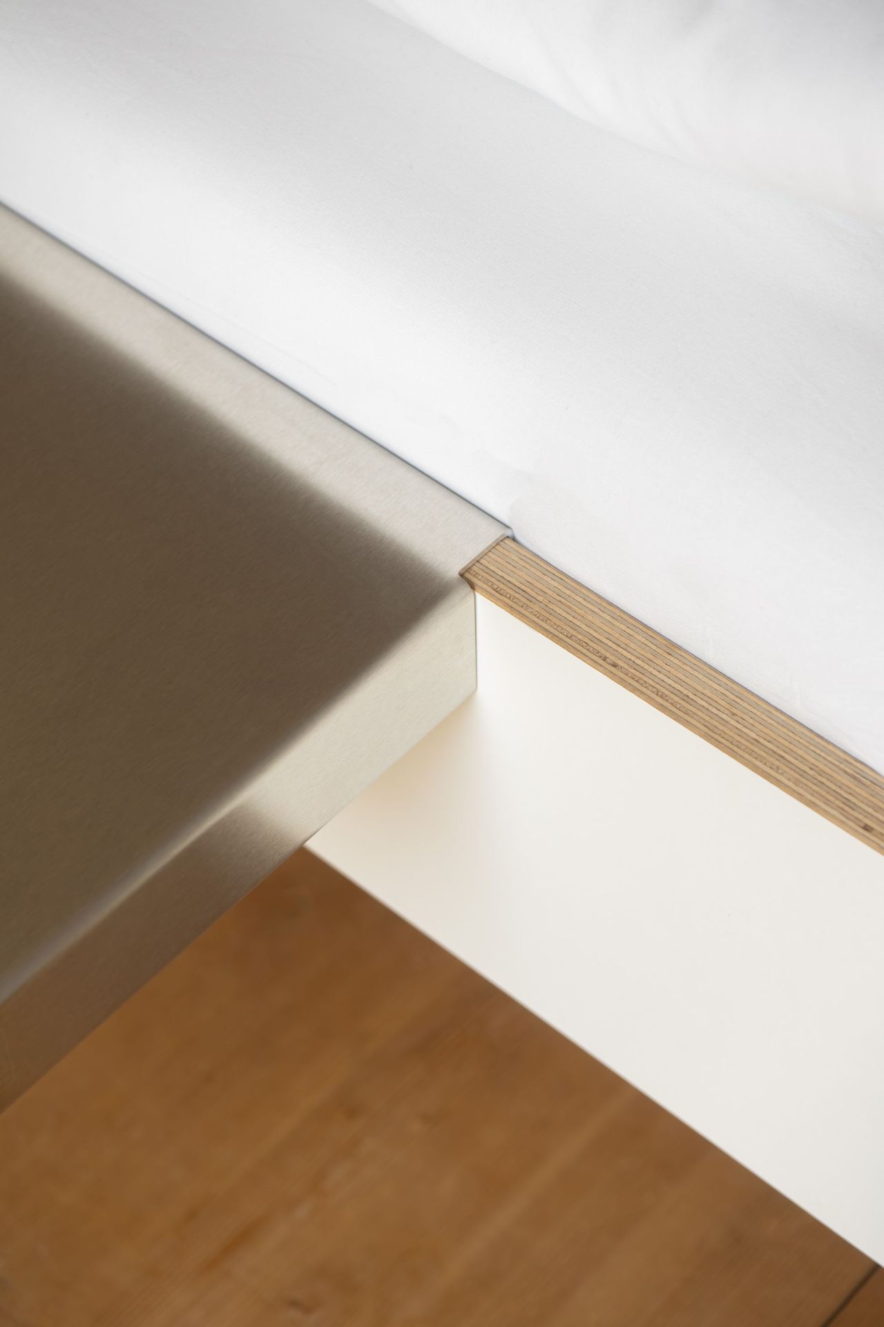 Detailaufnahme der Moormann Bettkante Leicht Seitenablage aus Metall und Holz am weißen Bett für Schlafzimmer.