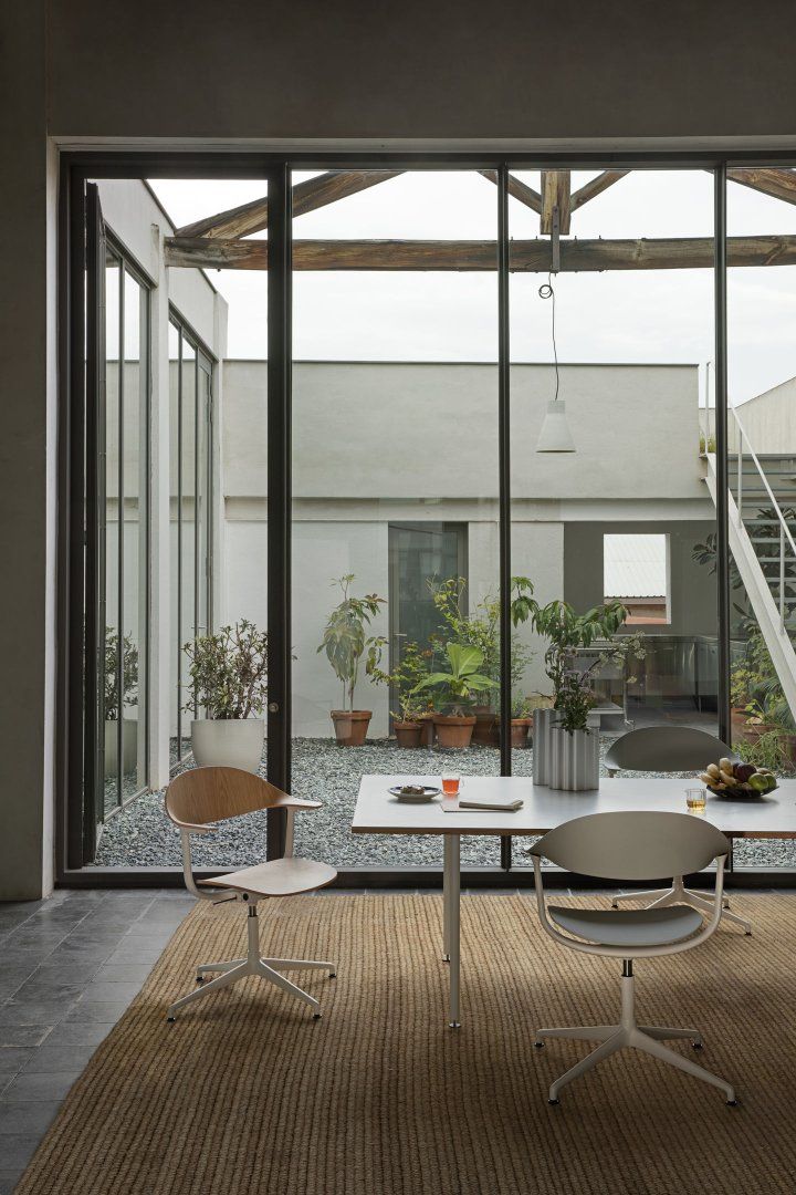 Mynt Bürodrehstühle von Vitra an Esstisch mit Blick in begrünten Innenhof.