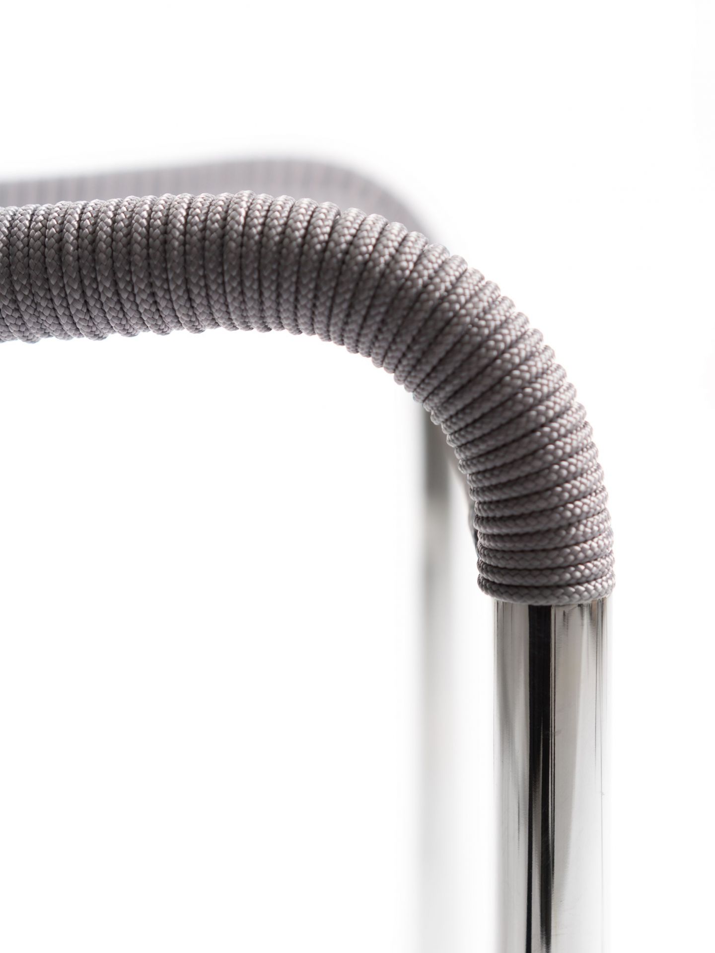 Detailaufnahme: Tecta B25 Kragstuhl, schwarzes Seilgeflecht auf verchromtem Stahlrohr, modernes Design.