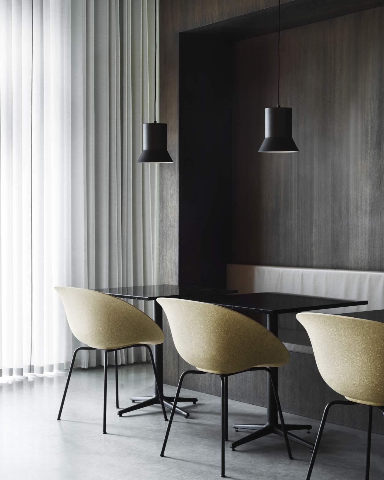 Mat Armchair von Normann Copenhagen mit Stahlarmlehnen in Beige an schwarzen Tischen unter Pendelleuchten.
