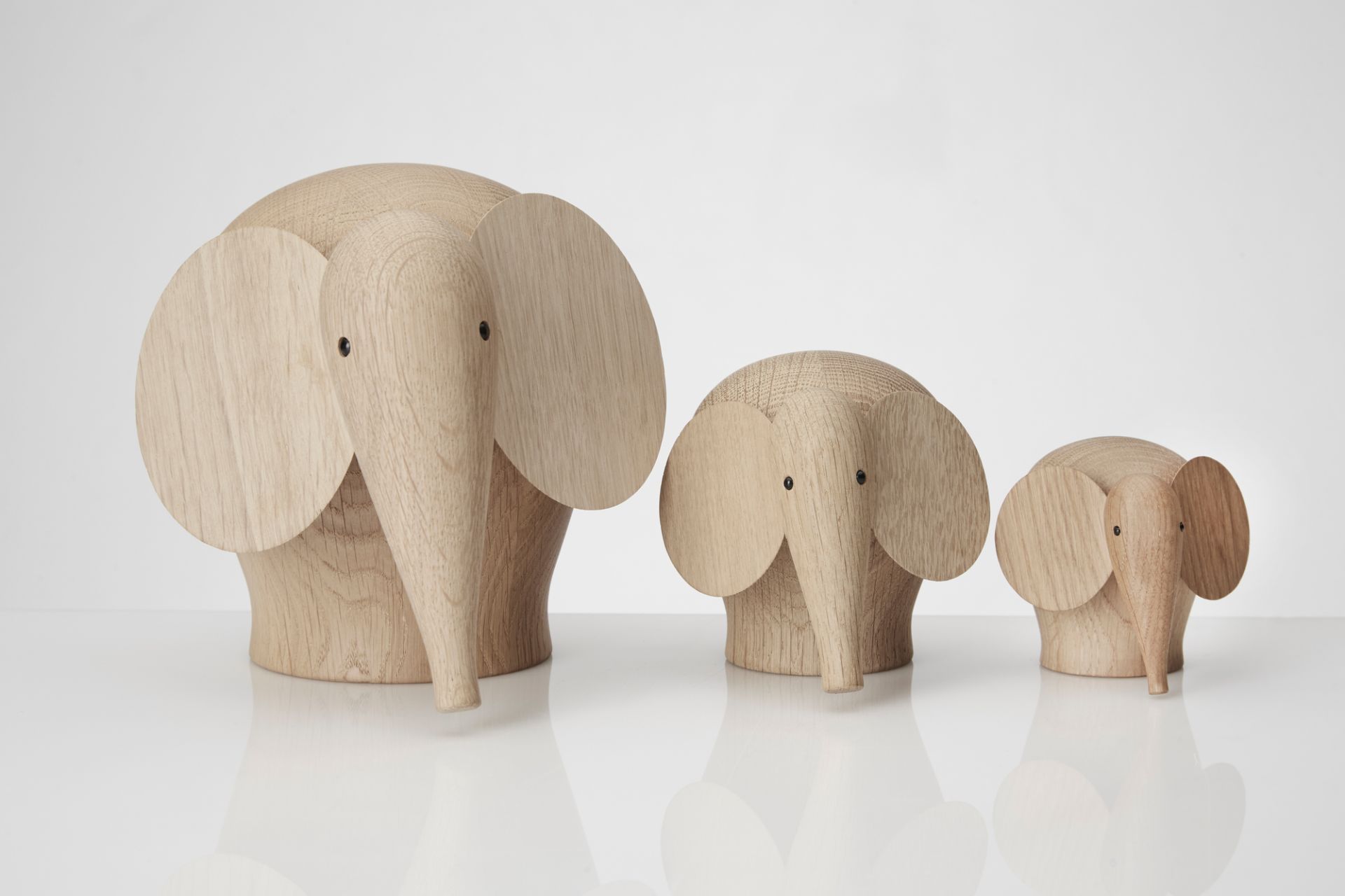 Drei Nunu Holzelefanten in verschiedenen Größen, dekorative Holzfiguren für Kinderzimmer und Wohnraum.