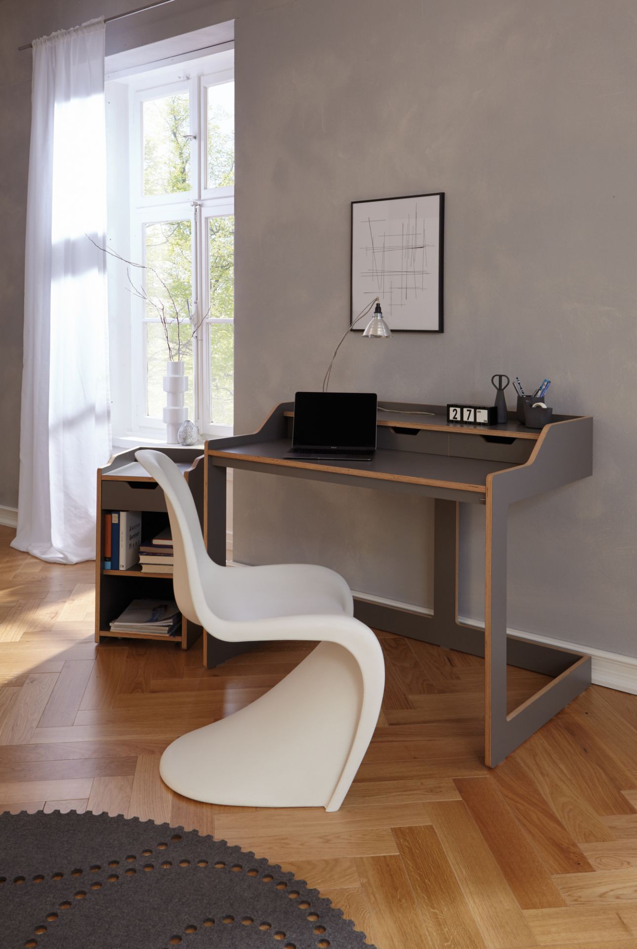 Moderner Schreibtisch mit Rollcontainer von Müller Möbelwerkstätten in grau mit Laptop und Büromaterial.