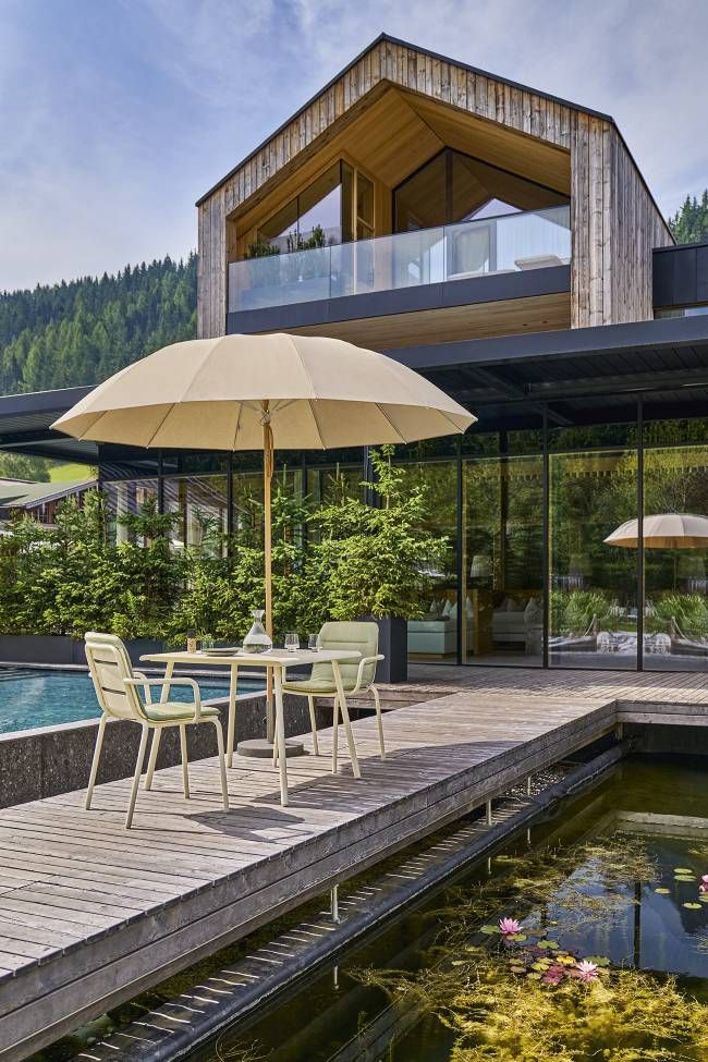 Weishäupl Vapio Tisch Outdoor mit zwei Stühlen und Sonnenschirm auf Holzterrasse am Pool.