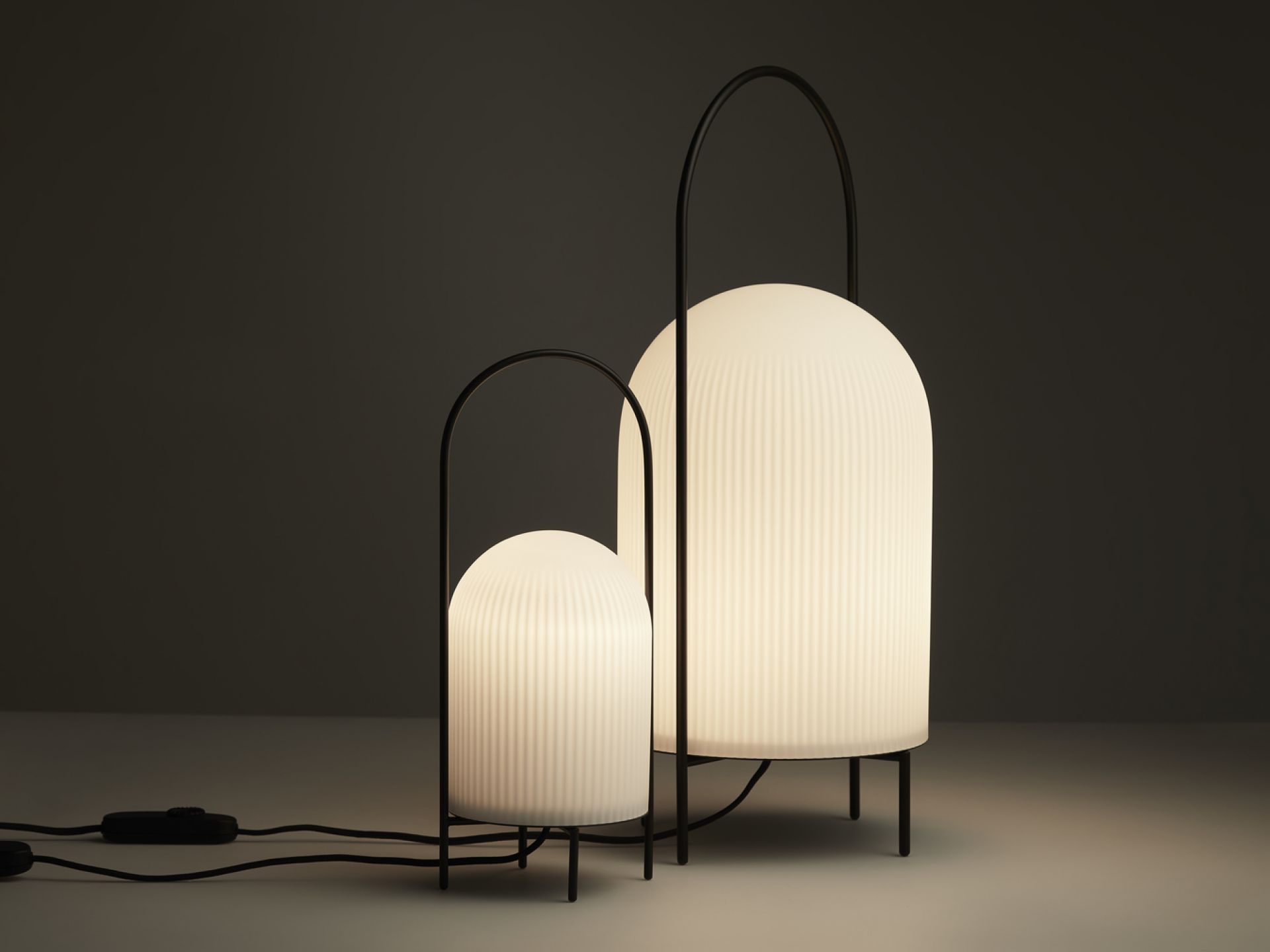 Zwei GHOST Stehleuchten von Woud, modernes Design mit gerippten, leuchtenden Schirmen und schwarzem Gestell.