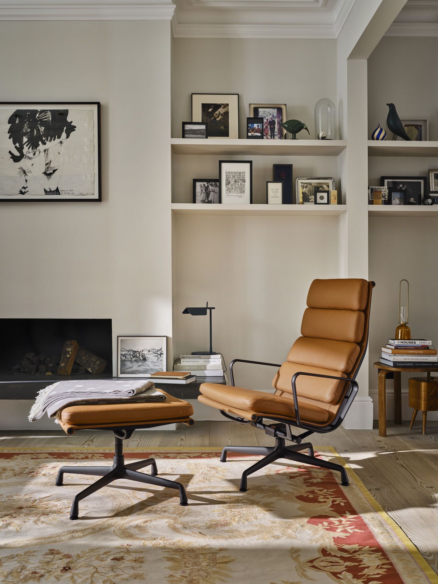 Vitra EA 222 Soft Pad Sessel mit Hocker in braunem Leder vor Kamin und Regal.