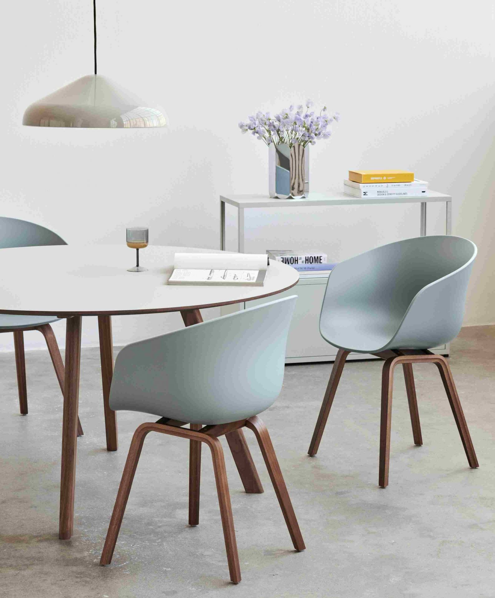 Esszimmer mit rundem Tisch, Stühlen mit Holzbeinen und Hay Arcs Vase L Mirror im Hintergrund.