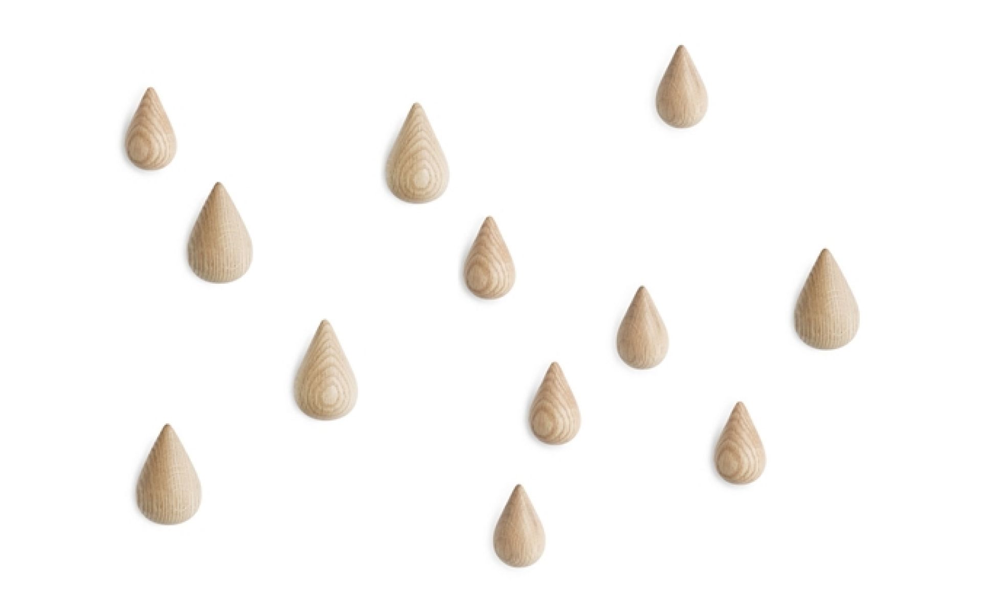 Nahaufnahme von mehreren Dropit Hooks Garderobenhaken von Normann Copenhagen in Tropfenform an einer weißen Wand.