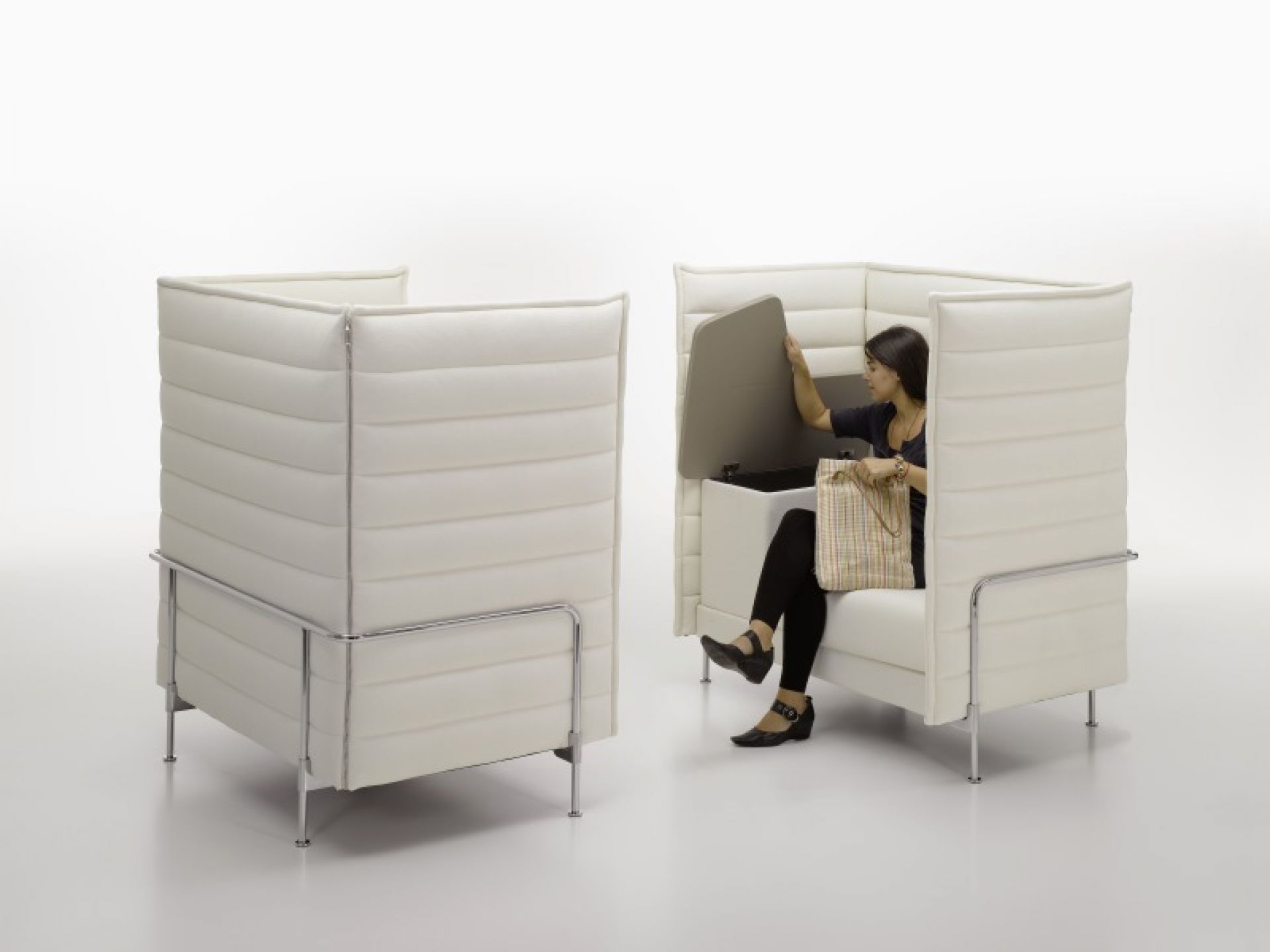 Vitra Alcove Highback Sessel: Frau öffnet Stauraum im weißen, hohen Bürosessel mit Chromgestell.