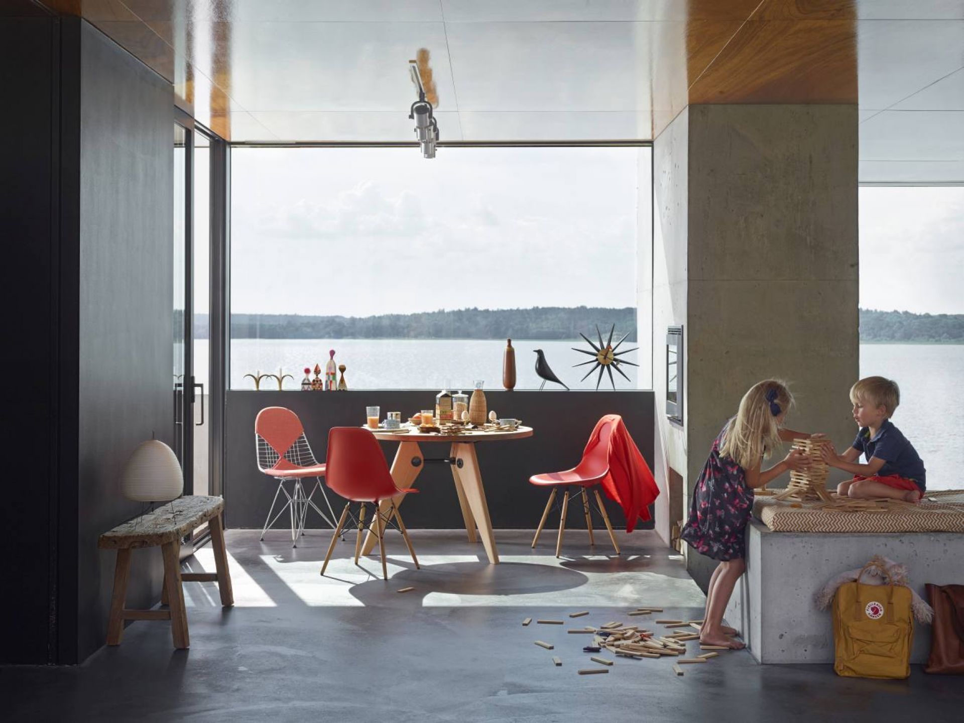 Heller Raum mit Vitra Guéridon Tisch aus Holz, Eames Stühlen und spielenden Kindern.