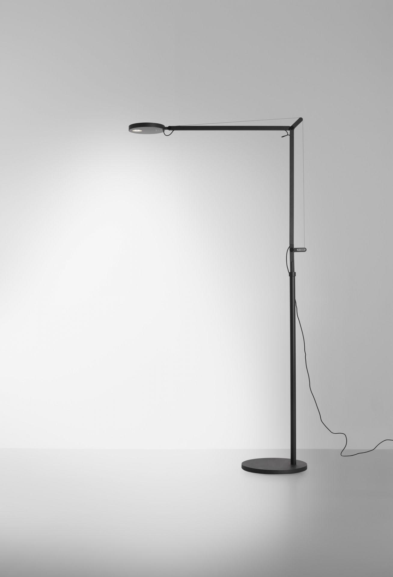 Schwarze Demetra Stehleuchte von Artemide mit rundem Fuß und verstellbarem Leuchtenkopf.
