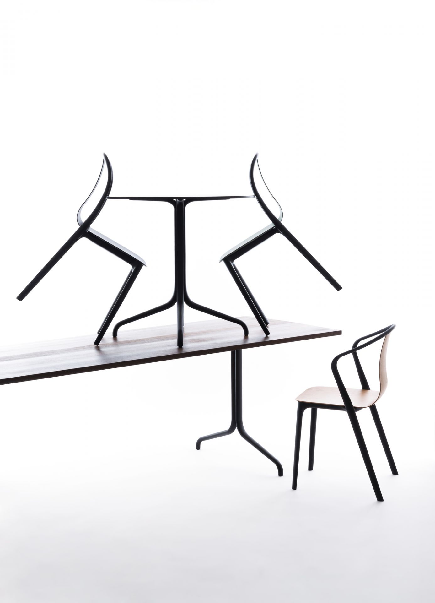 Vitra Belleville Chair Plastic Stuhl, schwarzes Gestell, Holz-Sitzfläche, zwei Stühle auf Tisch gestapelt.