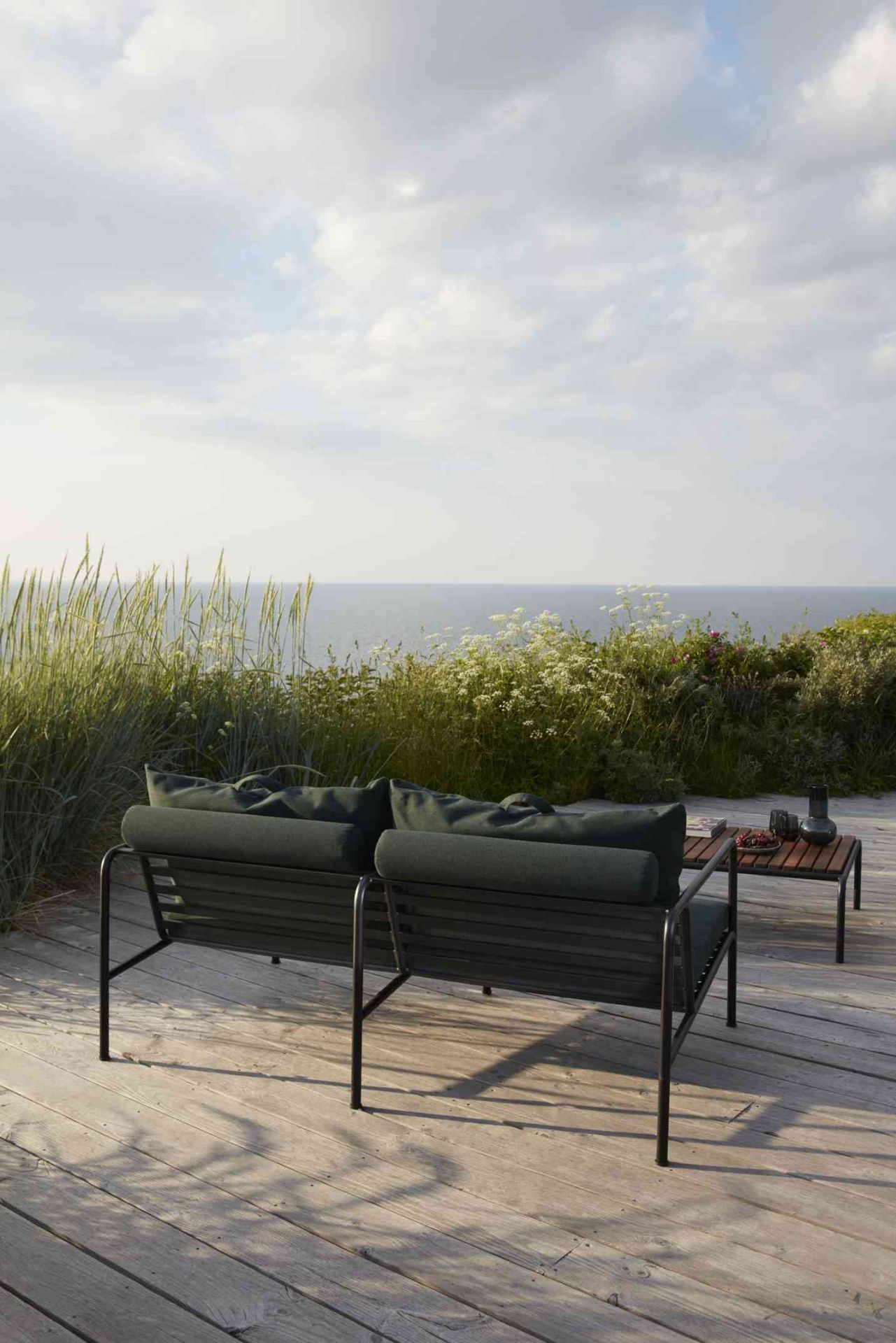 Avon Lounge Outdoor Tisch von Houe mit Sofa auf Holzterrasse am Meer.