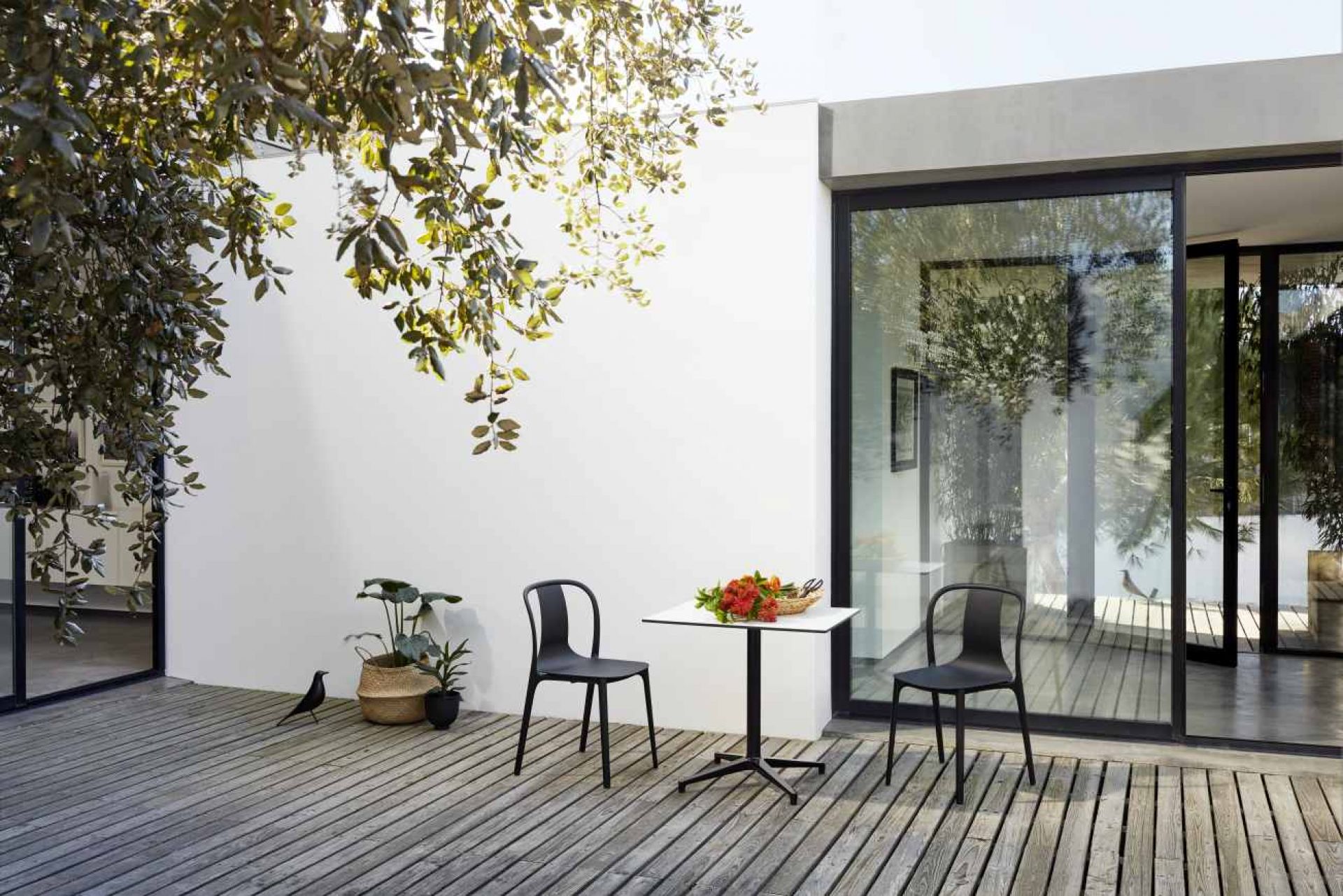 Rechteckiger Vitra Bistro Table Outdoor mit zwei schwarzen Stühlen auf einer Holzterrasse.