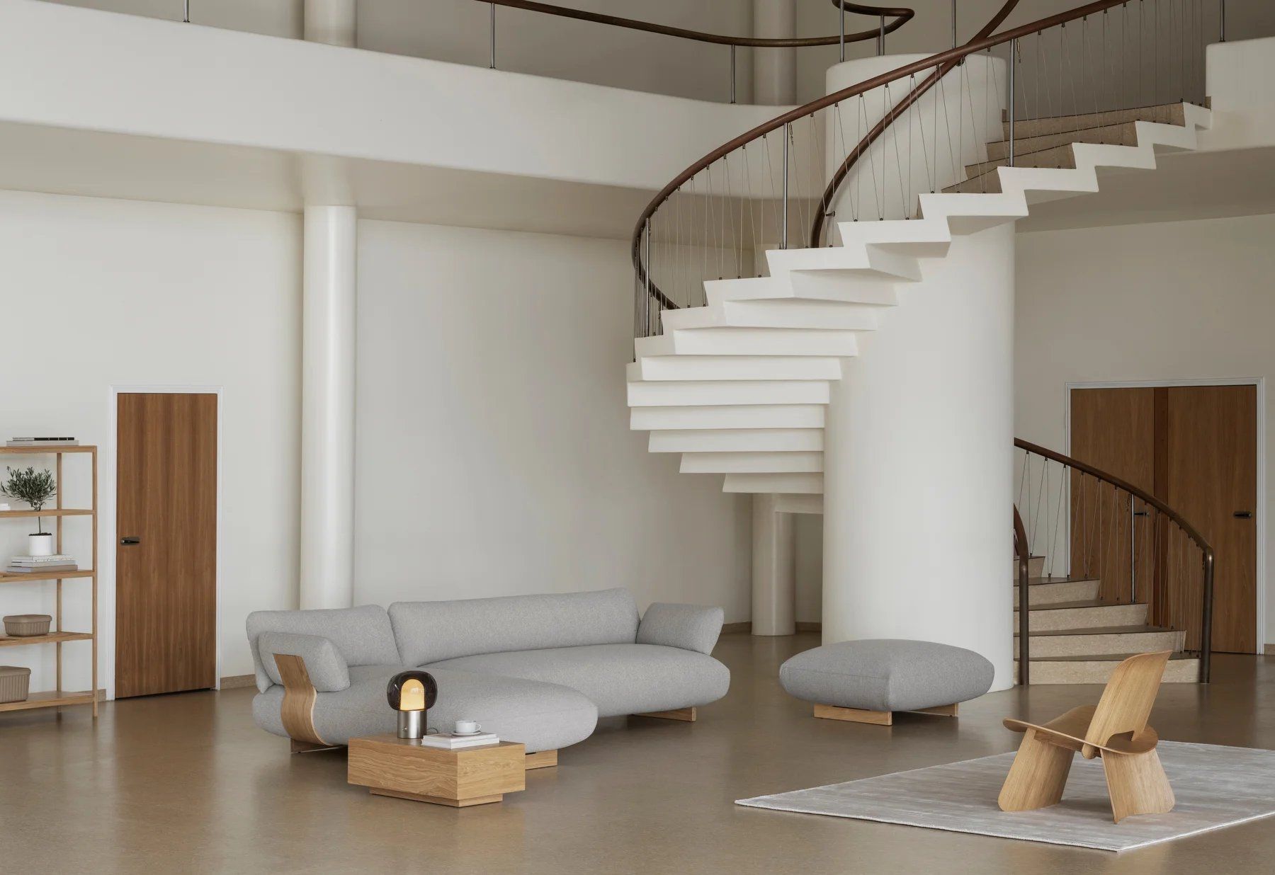 Heller Wohnraum mit grauer Couch, Hocker und einem hellen Nagomi Chair Stuhl von Blomus.