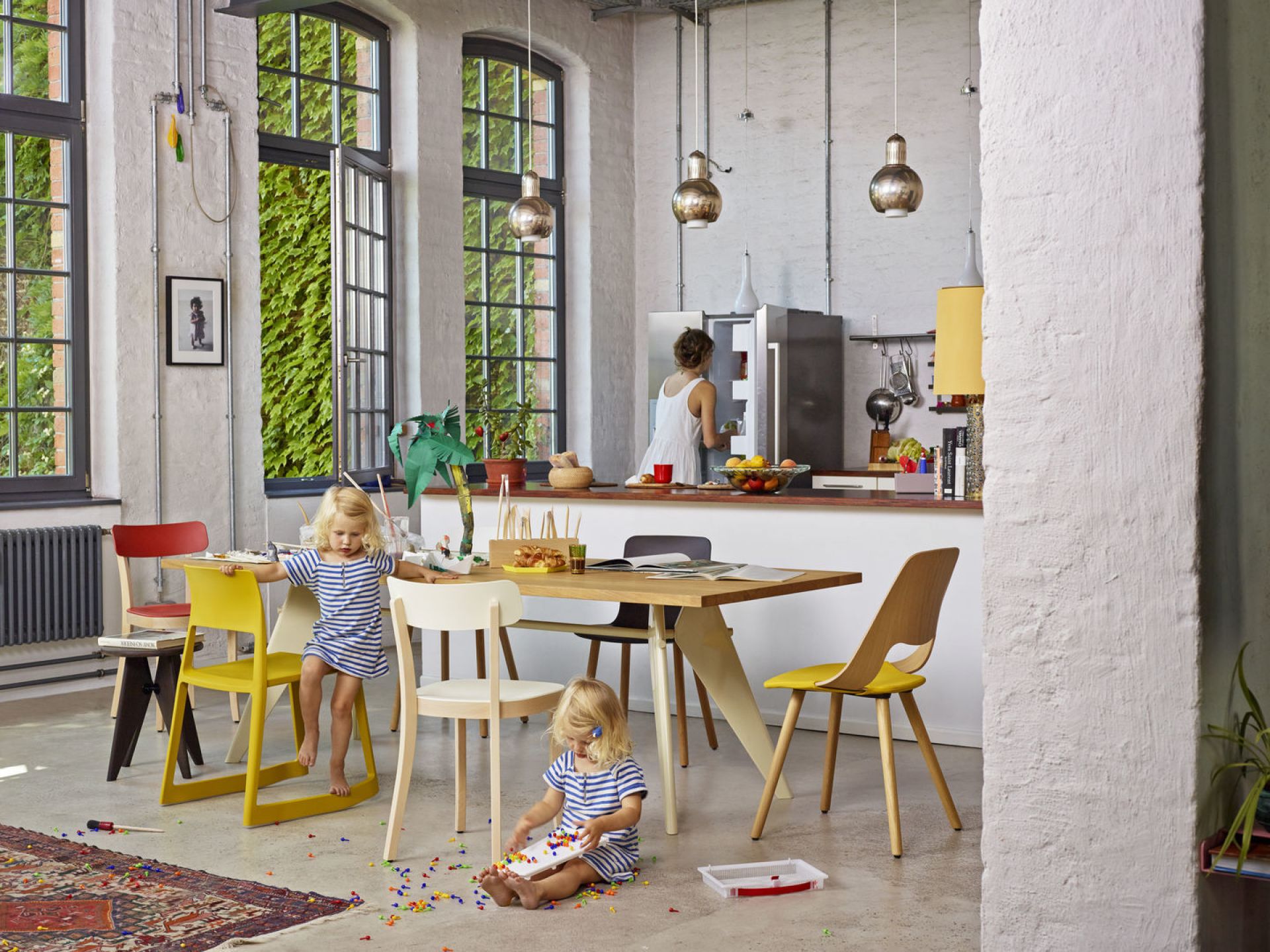 Esszimmer mit Kindern und verschiedenen Vitra Stühlen, darunter ein gelber Tip Ton Stuhl aus Kunststoff.