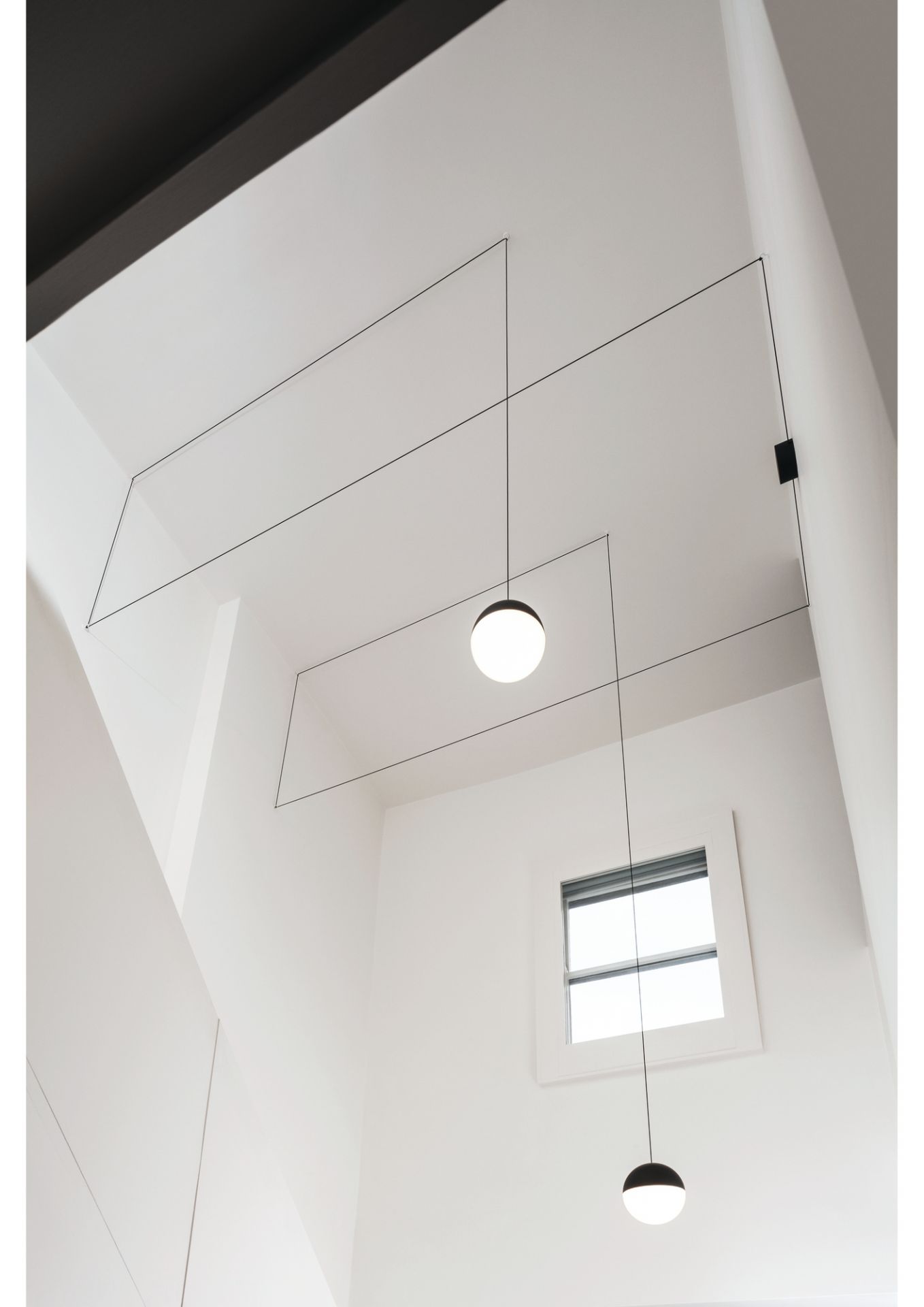 Flos String Light mit zwei Pendelleuchten und Wandrosette in modernem, weißem Interieur.