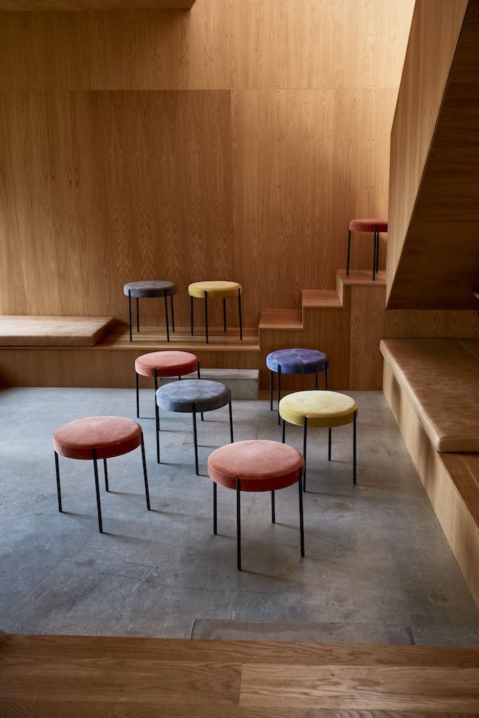 Mehrere farbige Series 430 Stool Hocker von Verpan in einem Raum mit Holzverkleidung und Sitzbänken.