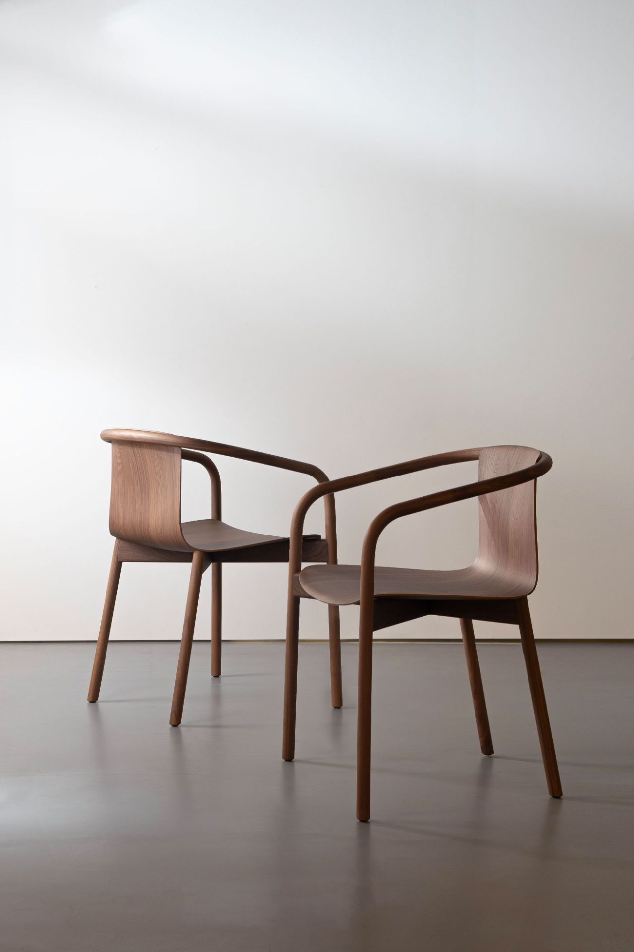 Zwei Osuu Stühle von Walter Knoll aus dunklem Holz vor einer weißen Wand.