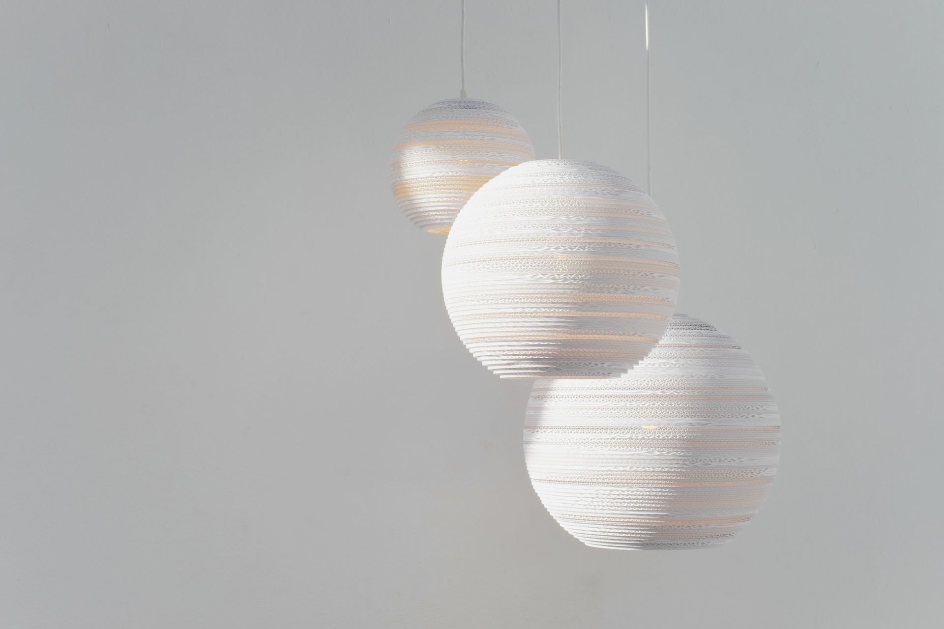 Drei weiße Scraplights Moon Hängeleuchten von Graypants, gefertigt aus recycelter Pappe, für stimmungsvolle Beleuchtung.