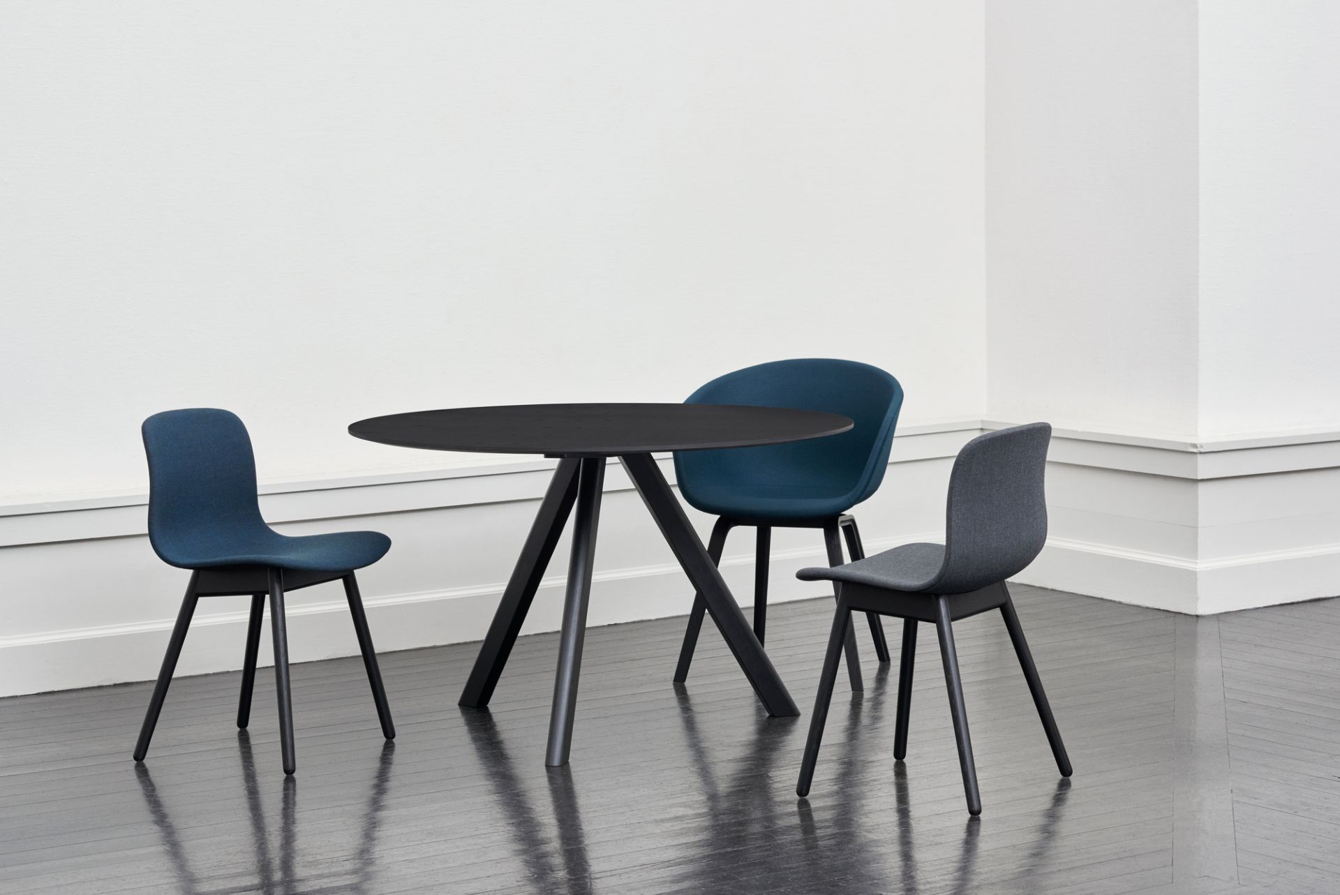 About A Chair AAC 13: Drei vollgepolsterte Hay Stühle in Blau und Grau um einen schwarzen Tisch.