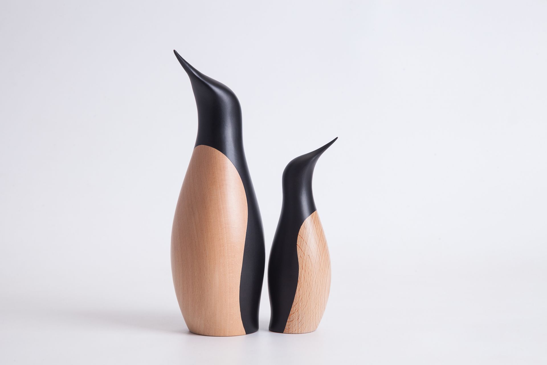 Zwei Architectmade Pinguin Holzfiguren, kleine und große Version, auf weißem Hintergrund.