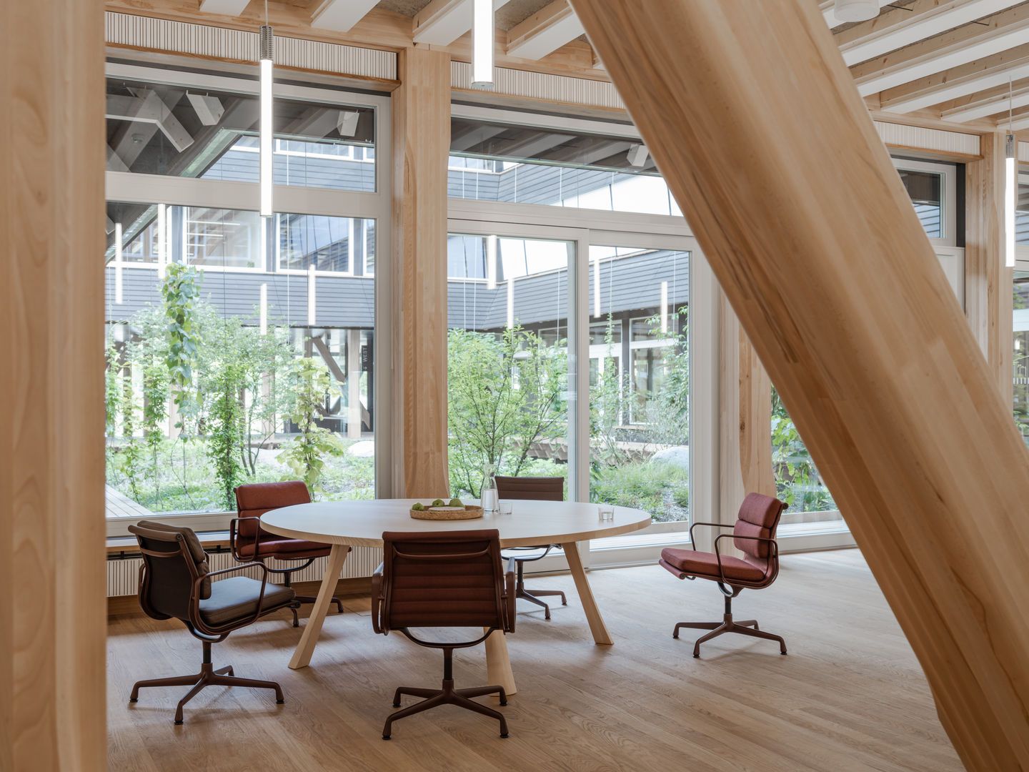 Innenaufnahme mit mehreren Aluminium Chair EA 108 Stühlen von Vitra um einen runden Tisch.