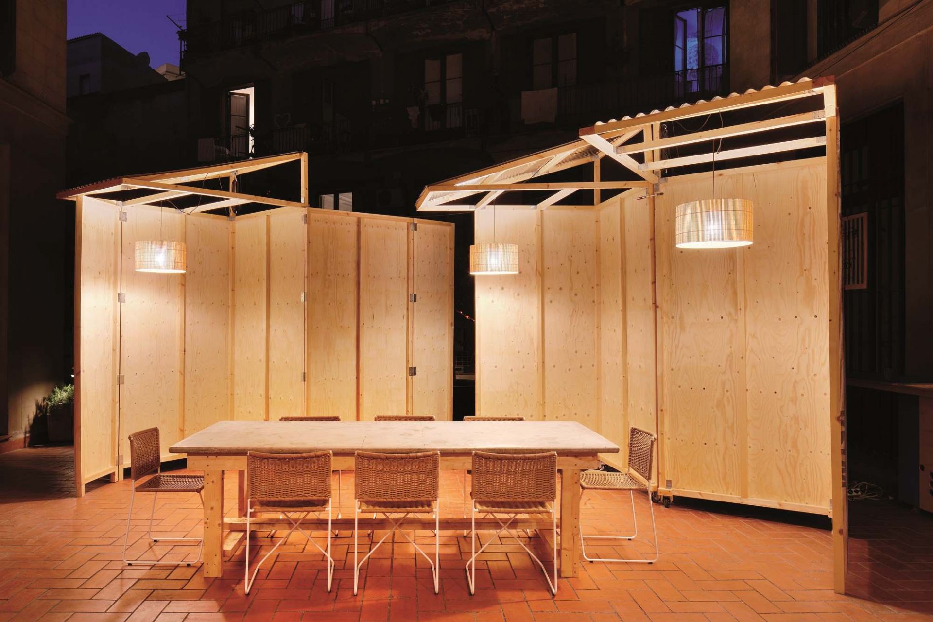 Rattanstühle von Santa & Cole um einen Holztisch mit passenden Rattan-Lampen.