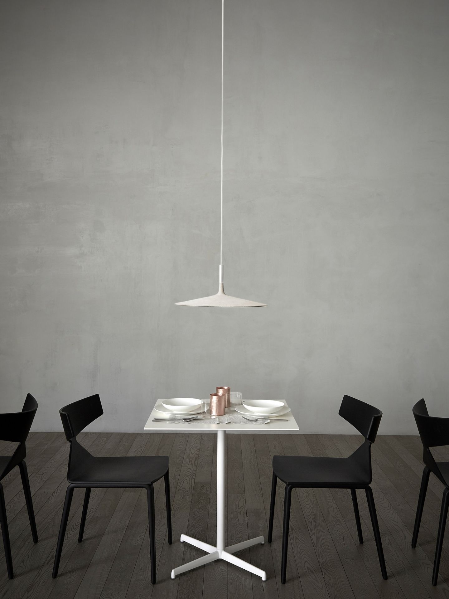 Aplomb LED Pendelleuchte von Foscarini in Weiß über Esstisch mit schwarzem Stühlen.