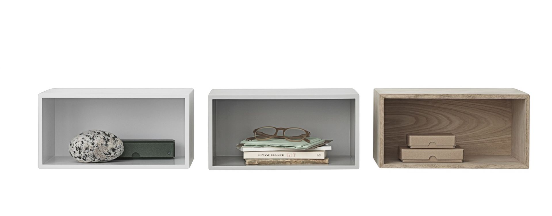 Muuto Mini Stacked Regalsystem 2.0, drei offene, unterschiedlich gefüllte Regalkuben in Weiß, Grau und Holz.