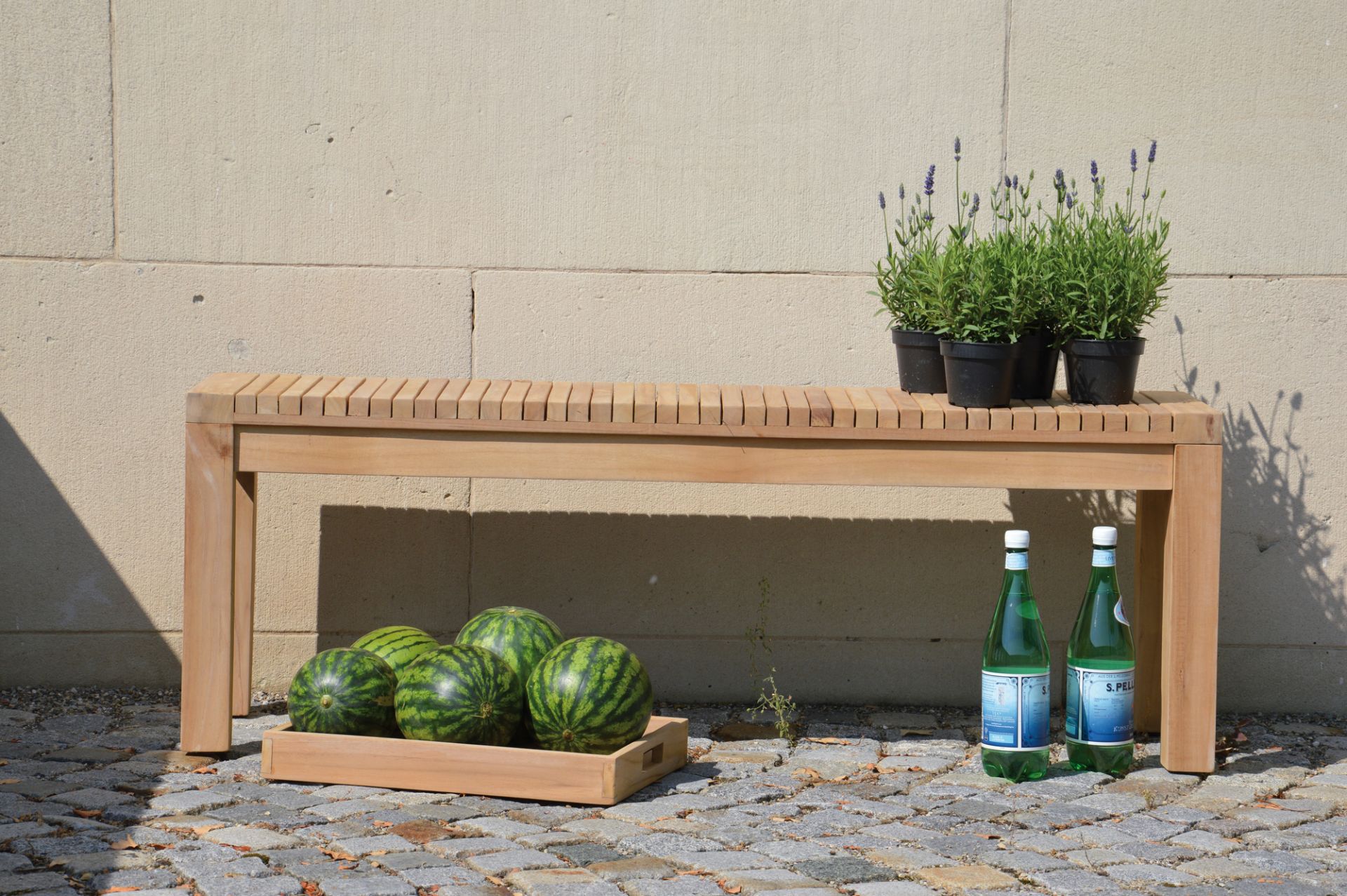 Samoa Bank von Jan Kurtz, Naturholz Gartenbank mit Melonen, Wasserflaschen und Lavendel.