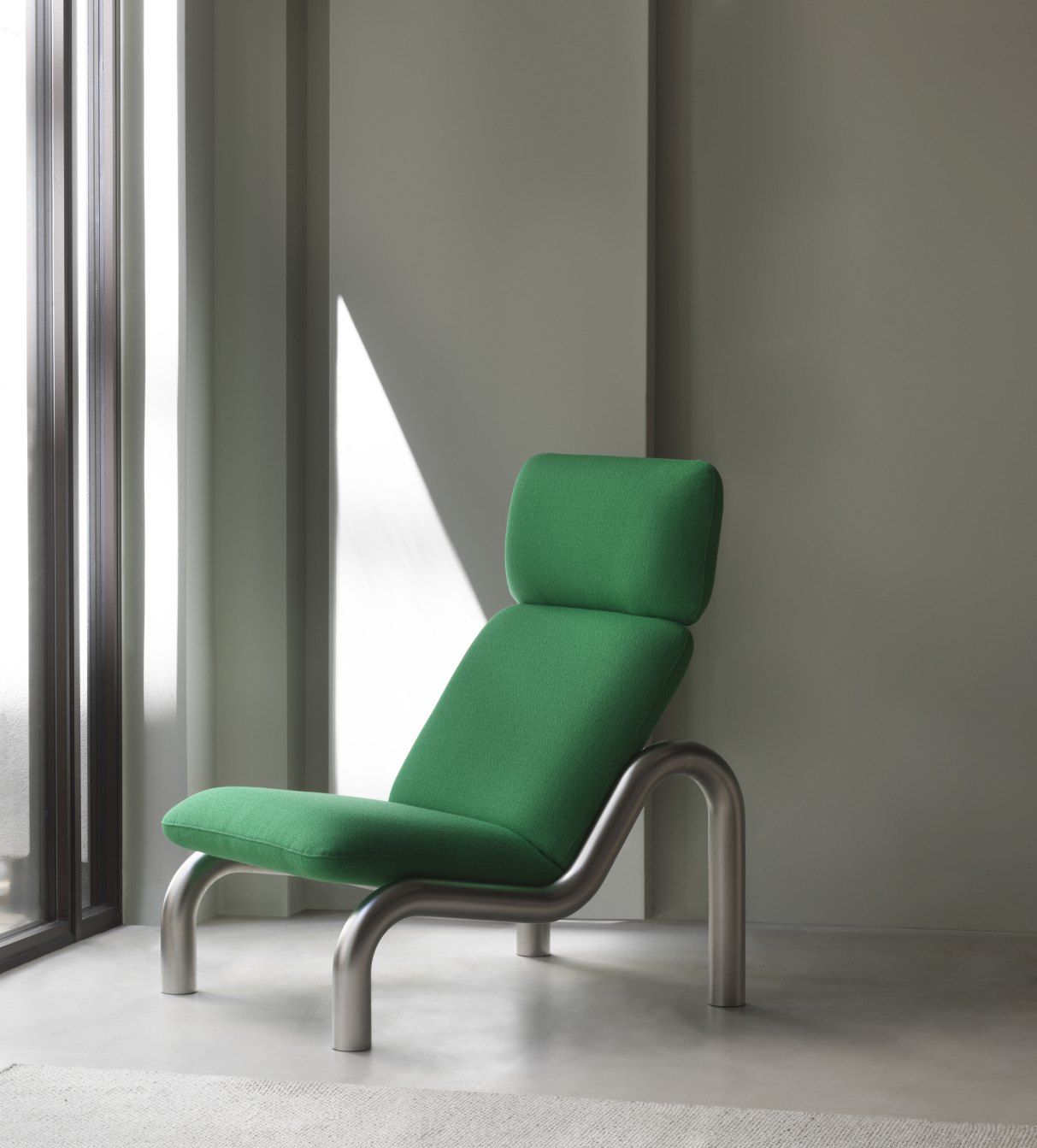 Grüner Tube Lounge Chair Sessel von Normann Copenhagen mit Stahlgestell vor Fenster.