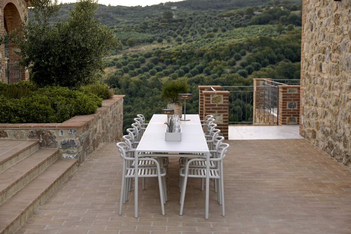 Dunkelgrüner Cane-Line Bliss Armchair Armlehnstuhl Outdoor auf einer Terrasse mit Blick auf die Landschaft.