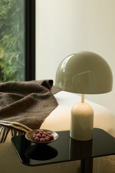 Bell Portable LED Tischleuchte von Tom Dixon in Kupfer auf einem Nachttisch.