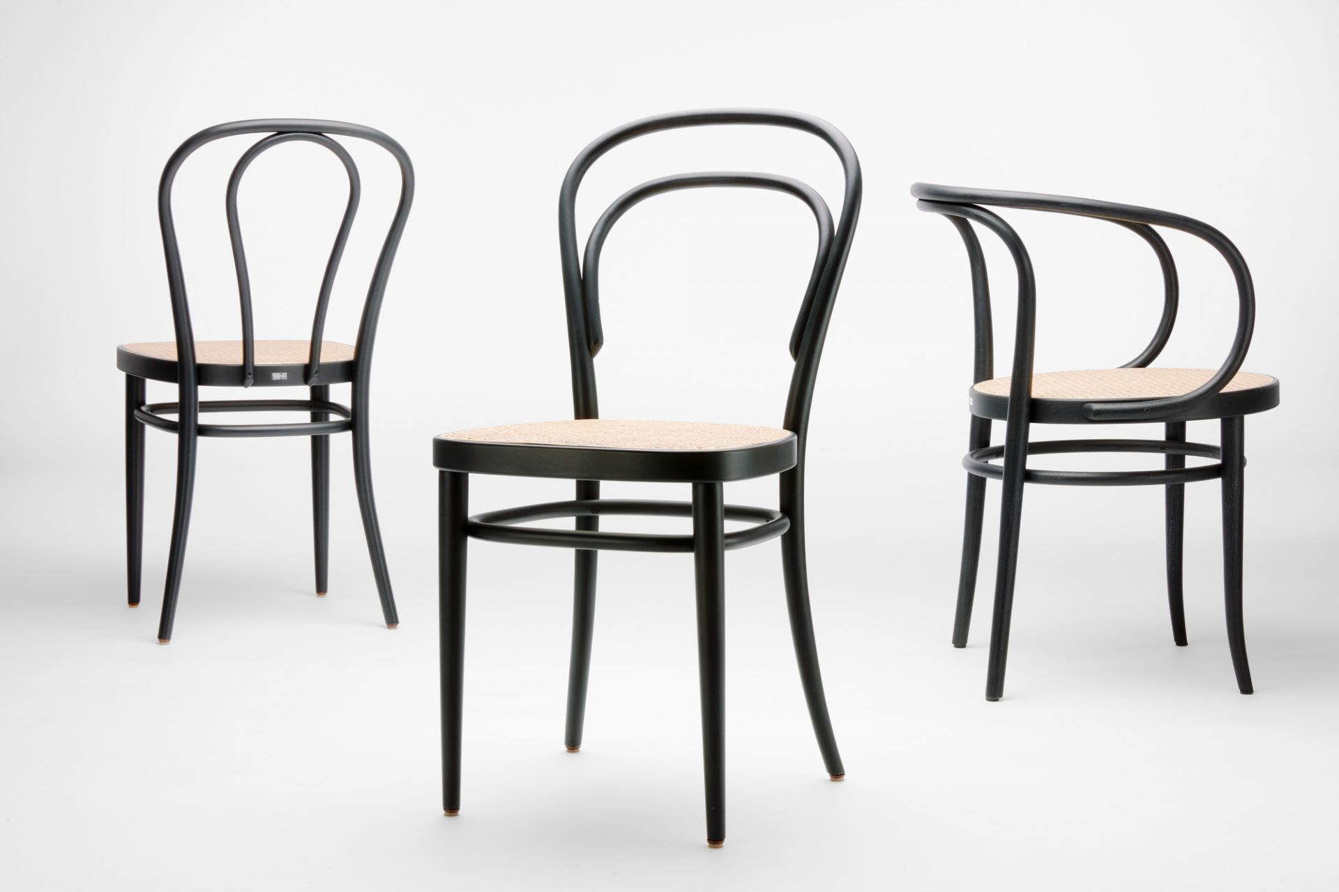 Drei schwarze Bugholzstühle, davon ein Stuhl mit Armlehne, Wiener Geflecht, Thonet-Stil.
