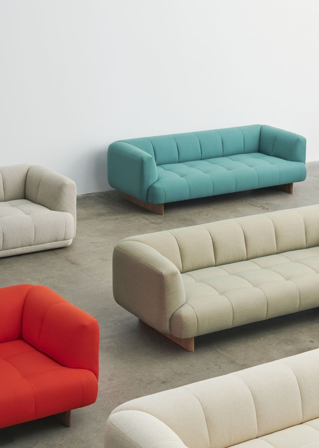 Mehrere moderne Quilton Sofas von Hay in verschiedenen Farben und Stoffen auf einem grauen Boden.