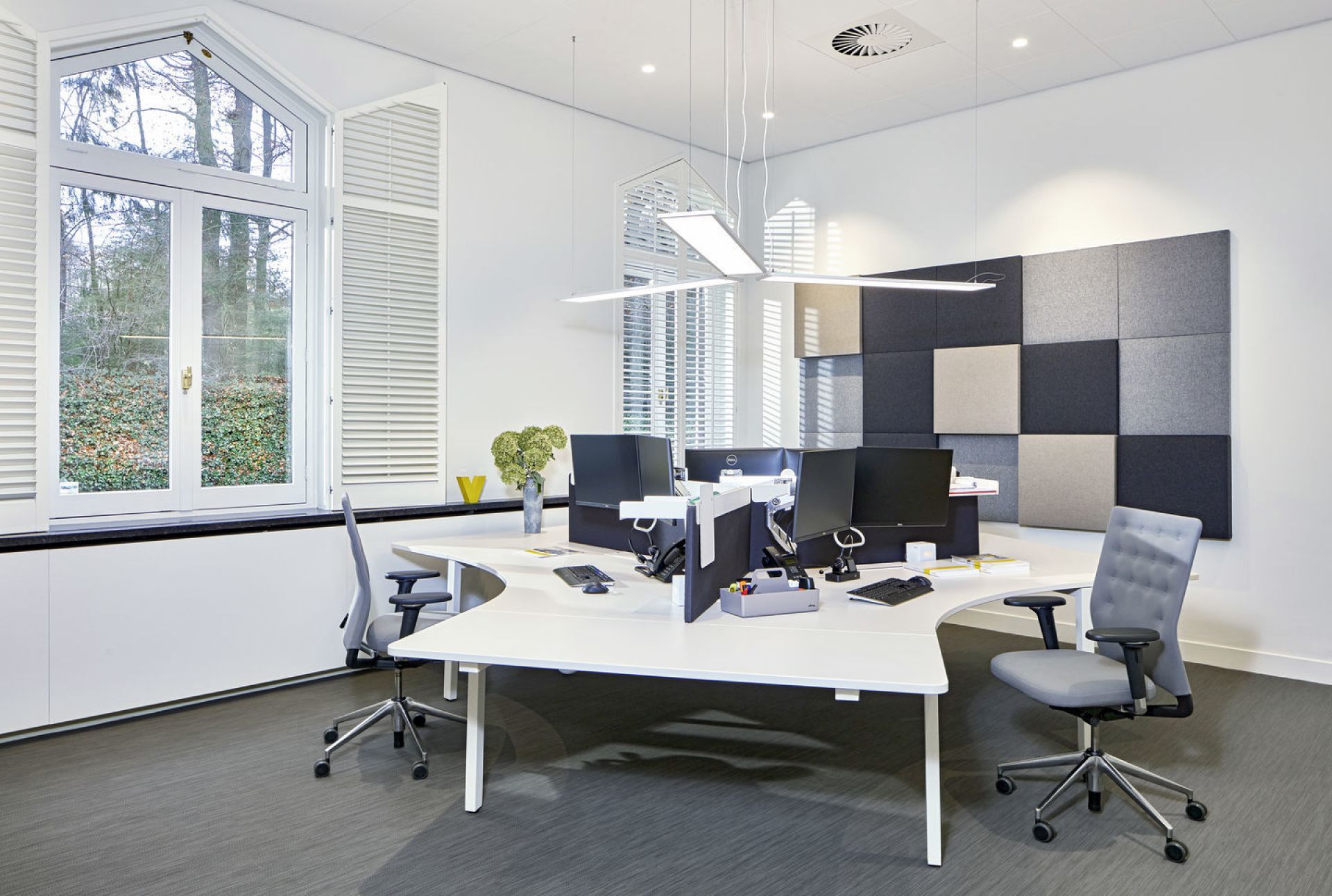 ID Trim Bürodrehstuhl von Vitra in modernem Büro mit Schreibtisch, Computern und Akustikpaneelen.