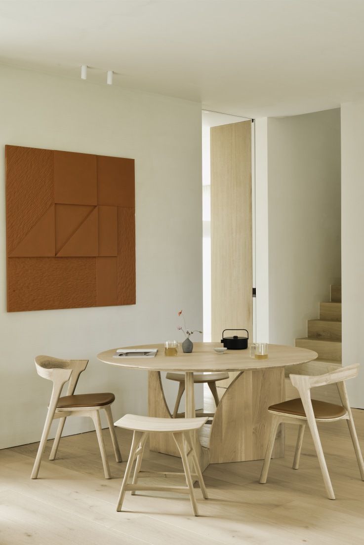 Ethnicraft Esstisch Geometric Dining Table aus hellem Holz mit Stühlen und Dekoration in modernem Ambiente.