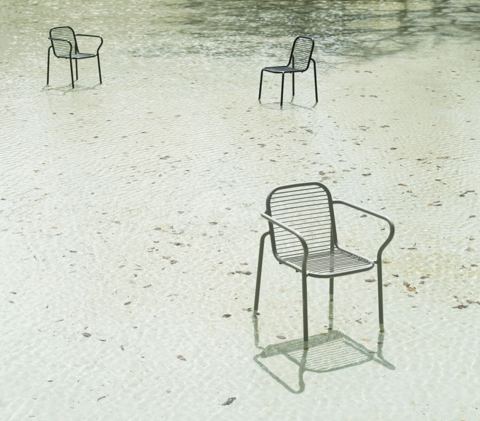 Drei graue Vig Chair Stühle von Normann Copenhagen stehen im flachen Wasser, Outdoor Möbel.