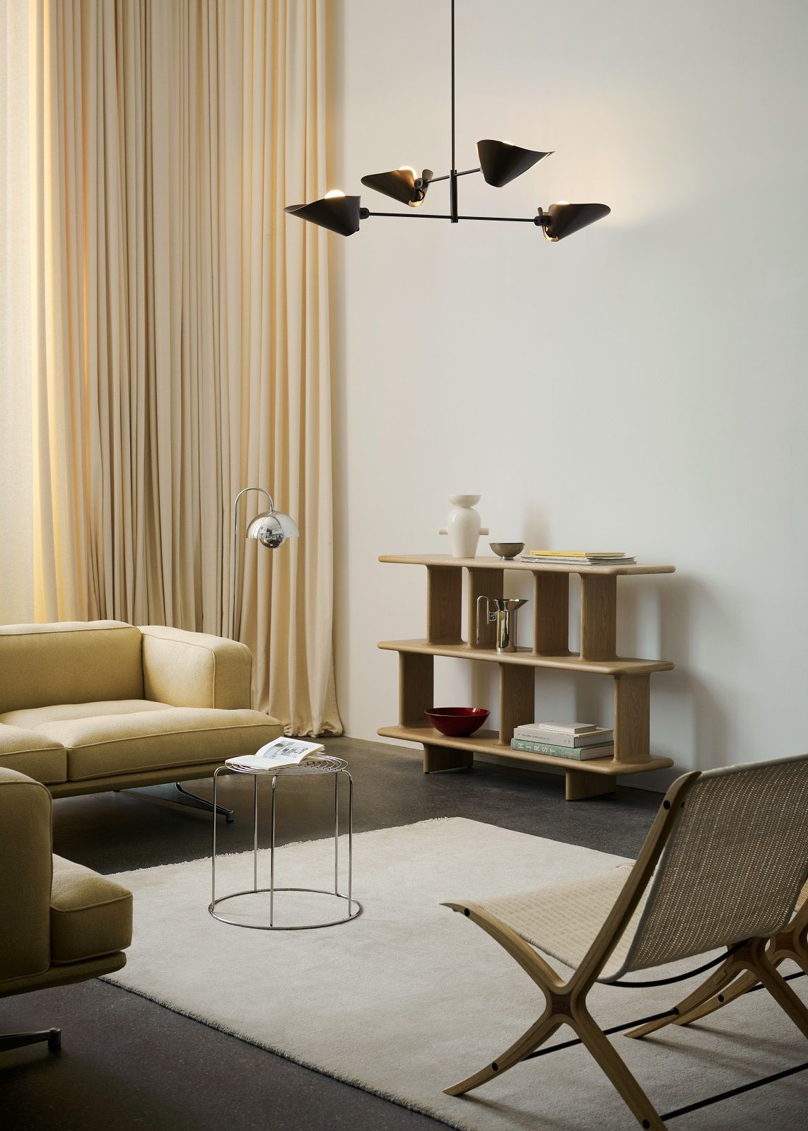 Beiger The Moor Teppich von AndTradition in einem modern eingerichteten Wohnzimmer mit Sofa und Regalen.
