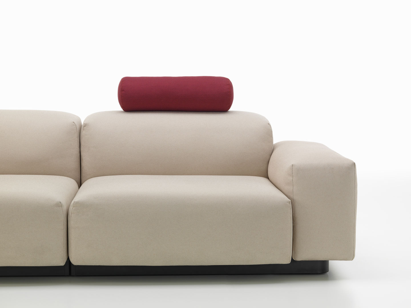 Beige Couch mit rotem, zylindrischem Vitra Kissen als Sofakissen zur Dekoration und bequemen Rückenlehne.